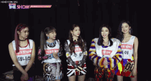 a group of girls standing next to each other with the show written on the bottom left