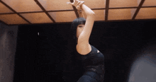 a woman in a black dress is dancing in a dark room with a wooden ceiling