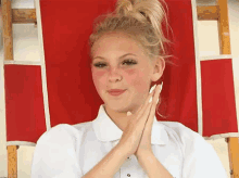 a girl with red cheeks is sitting in a red chair