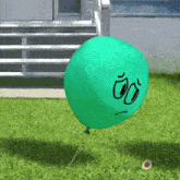 a green balloon with a sad face is floating in the air