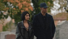 a man and a woman are standing next to each other in a cemetery holding hands .