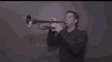 a man in a black shirt is playing a trumpet in a dark room