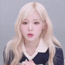 a close up of a woman with blonde hair wearing a blue sweater and a white collar .