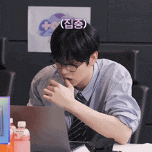 a man wearing glasses and a tie is sitting in front of a laptop computer