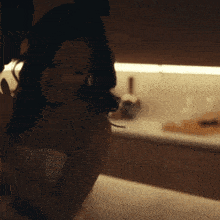 a woman in a white top stands in a kitchen
