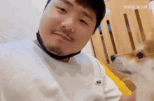 a man wearing a white shirt with the letter l on it looks at a small dog