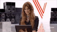 a woman sitting in front of a stack of speakers looking at her tablet