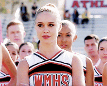 a cheerleader for wmhs stands in front of a crowd of people