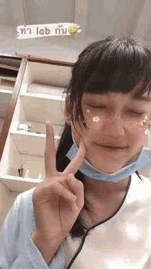 a girl wearing a face mask is making a peace sign with her fingers