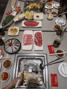a hot pot is being cooked on a table with plates of food