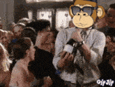 a man is holding a bottle of champagne in front of a crowd with a monkey on his head .