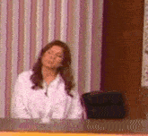 a woman in a white shirt is sitting at a desk with her head down .