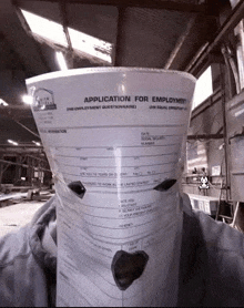 a person is holding a piece of paper that says application for employment on it .
