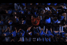 a group of people wearing blue shirts are sitting on the floor