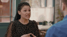 a woman in a black polka dot dress is talking to a man