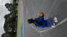 a girl in a blue shirt is holding a basketball on a basketball court