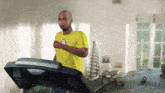 a man running on a treadmill wearing a yellow shirt with a cloud on it
