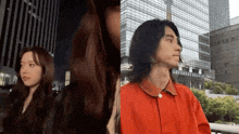 a woman and a man are standing next to each other in front of tall buildings