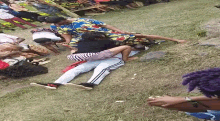 a group of people laying on top of each other in the grass .
