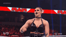 a woman in a black leather outfit is standing in a wrestling ring