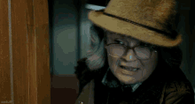 an older woman wearing a hat and glasses is smiling and looking at the camera