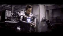 a man in a iron man suit is sitting in a chair in a garage .