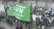 a crowd of people are holding a green banner that says econ