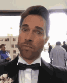 a man in a tuxedo with a bow tie is making a funny face