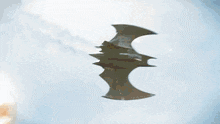 a bat is flying through a blue sky in front of an explosion .