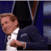 a man in a suit and tie is making a funny face while sitting on a stage .