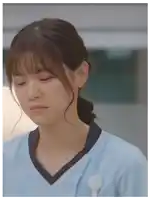 a close up of a woman wearing a blue scrub top making a face