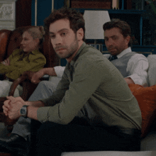 a man in a green shirt is sitting on a couch