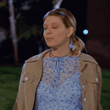 a woman wearing a blue shirt and a tan jacket looks down