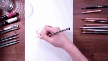 a person drawing on a piece of paper with a pen that says uni