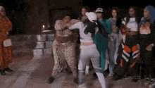 a group of women are dancing together and one of them is wearing a leopard print jumpsuit .
