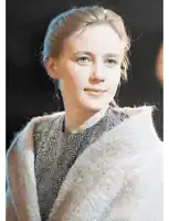a woman wearing a grey sweater and a white blanket around her neck