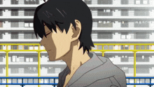 a man in a grey hoodie stands in front of a building with his eyes closed