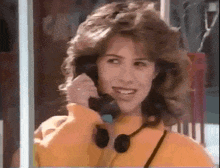 a woman in a yellow jacket is talking on a telephone .