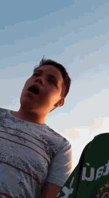 a young boy is looking up at the sky while wearing a shirt that says heineken
