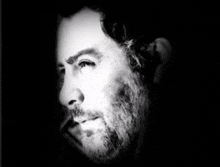 a black and white photo of a man 's face with a beard .