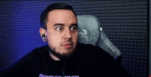 a man with a beard is wearing headphones and making a funny face while sitting in a gaming chair .