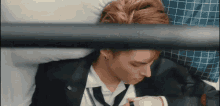 a man in a suit and tie is laying on a bed and looking at his watch .