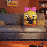 a stuffed duck sits on a couch reading a book called superhero