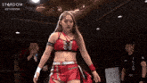 a woman stands in front of a microphone with the word stardom on the bottom right