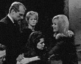 a black and white photo of a group of people standing next to each other in a dark room .