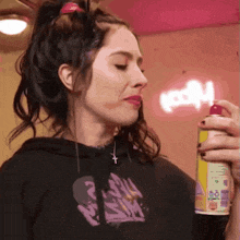 a woman in a black hoodie is spraying a can of spray