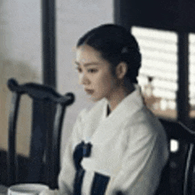 a woman in a kimono is sitting in a chair .