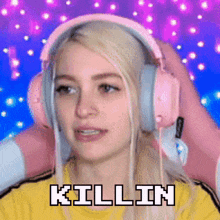 a woman wearing pink headphones and a yellow shirt with the words killin written on it .