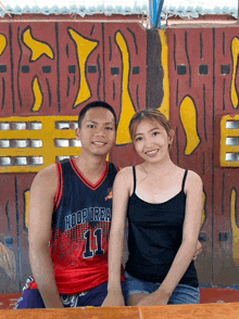 a man and a woman pose for a picture with the man wearing a hoop urea 11 jersey