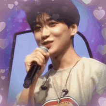 a young man is singing into a microphone with hearts surrounding him